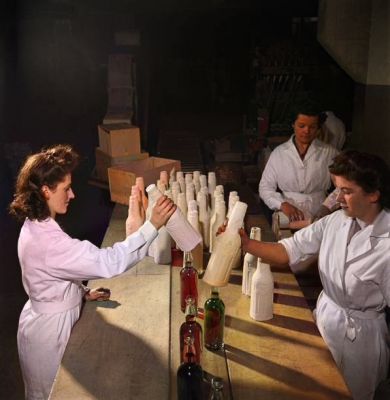 Female employees pack glass bottles of White Horse brand Scotch whisky in safety cartons at the Port Dundas distillery and bottling plant in Glasgow, Scotland during World War II on 3rd April 1945
